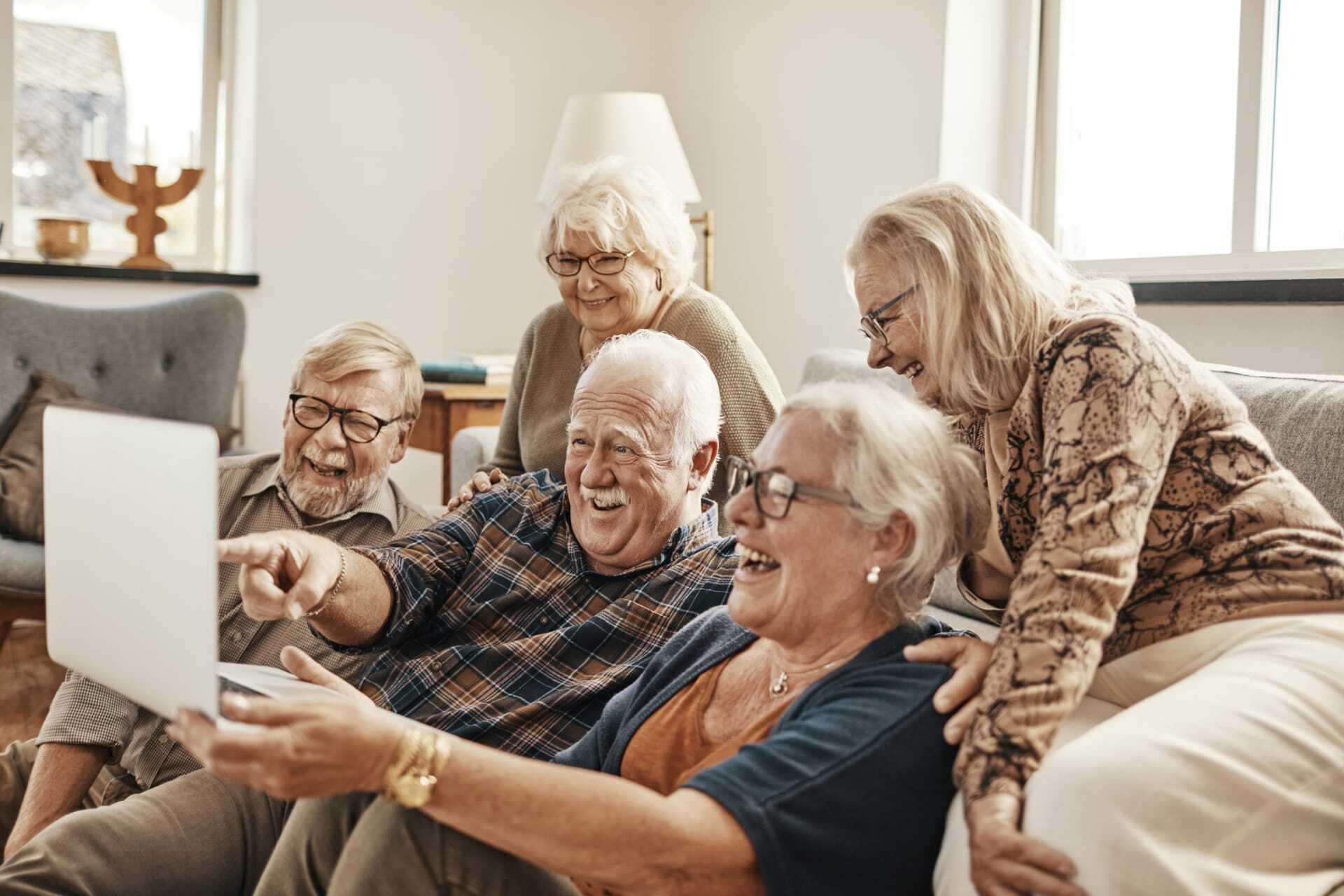 group of residents laughing at video on a laptop